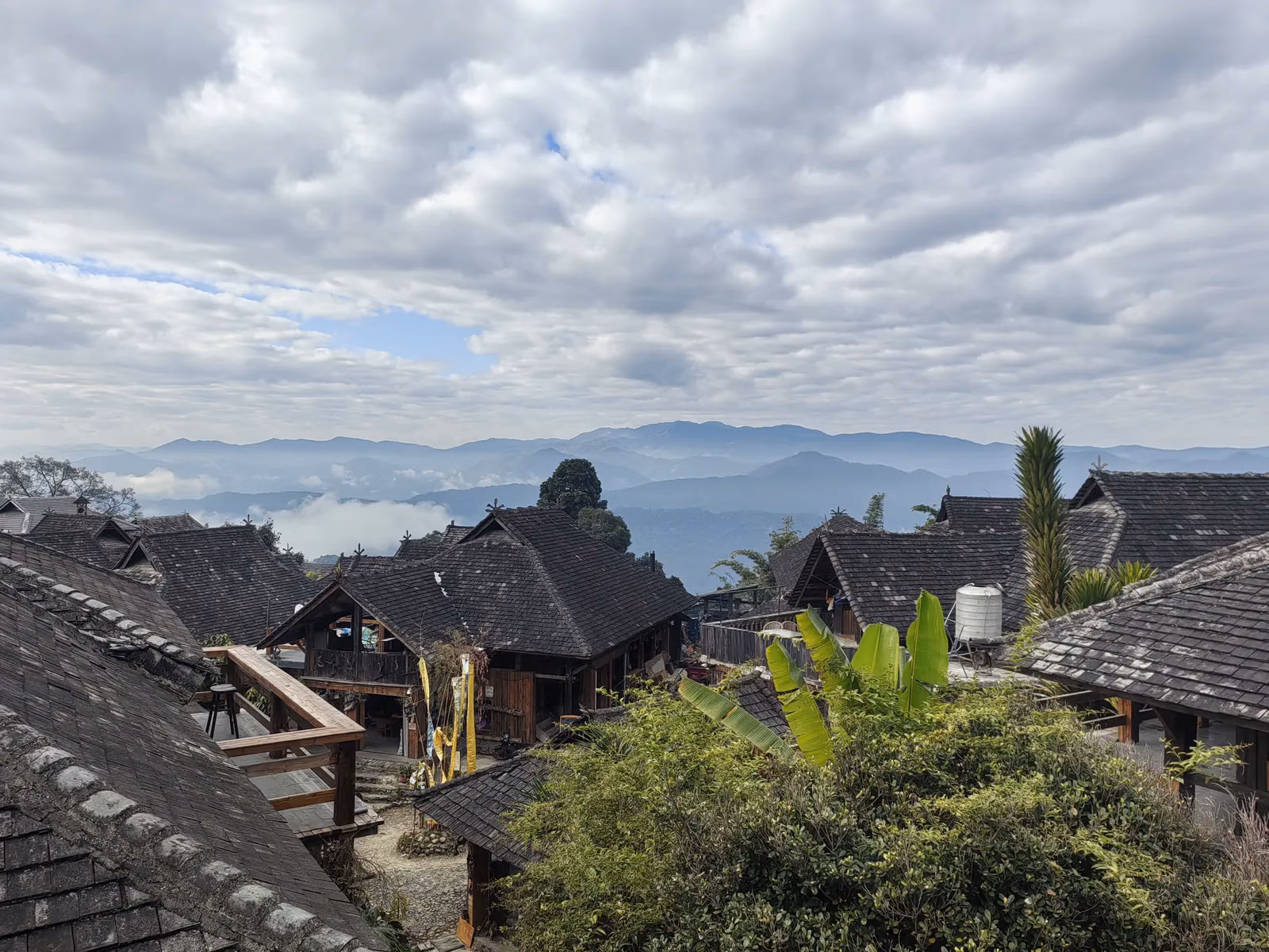 Nhà gỗ và mái ngói ở làng Ông Cơ, phía xa là núi