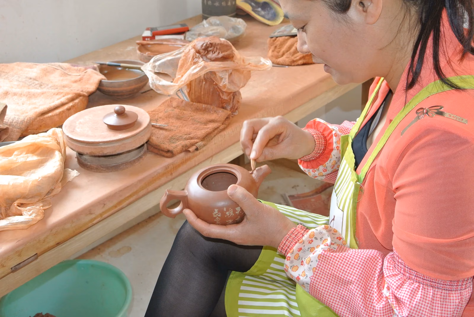 An artisan works on the spout of a Jianshui purple pottery teapot