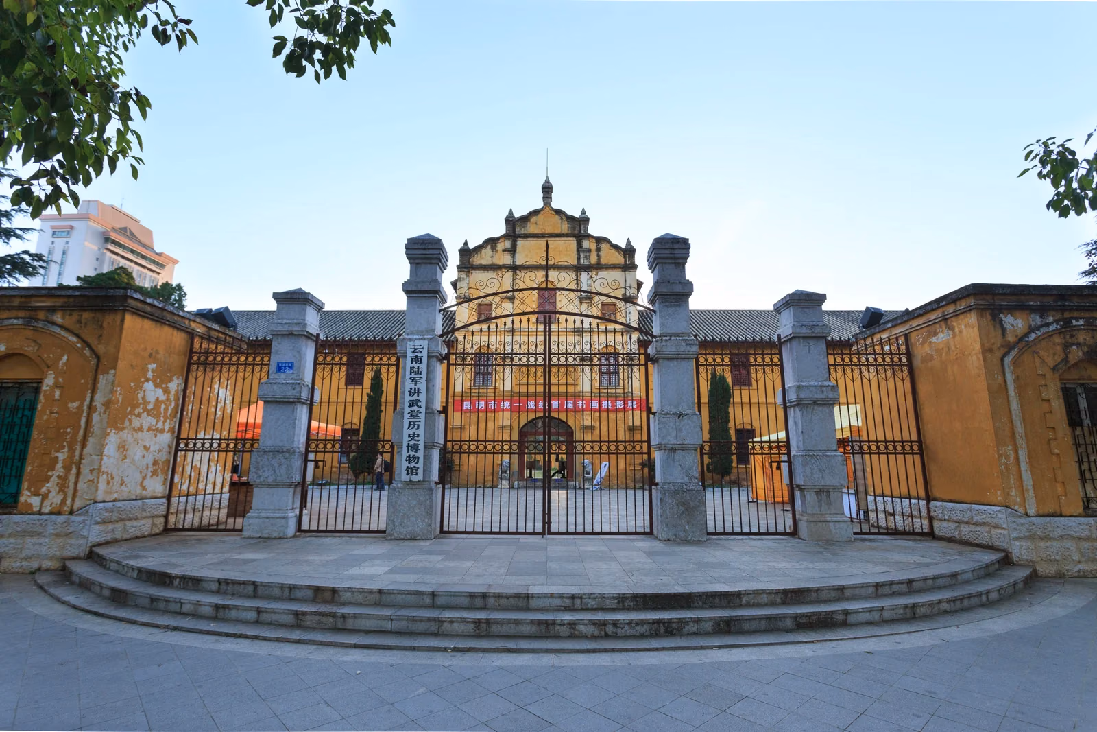 Iron entrance gates and yellow facade of the Yunnan Military Academy in Kunming