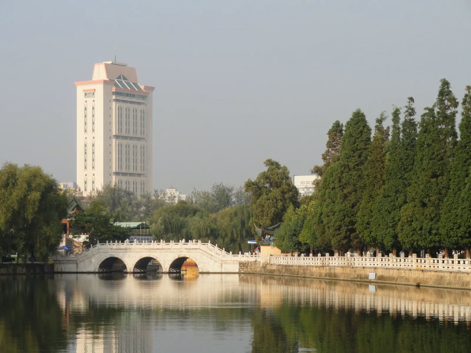 An arched bridge and trees beside Green Lake in central Kunming