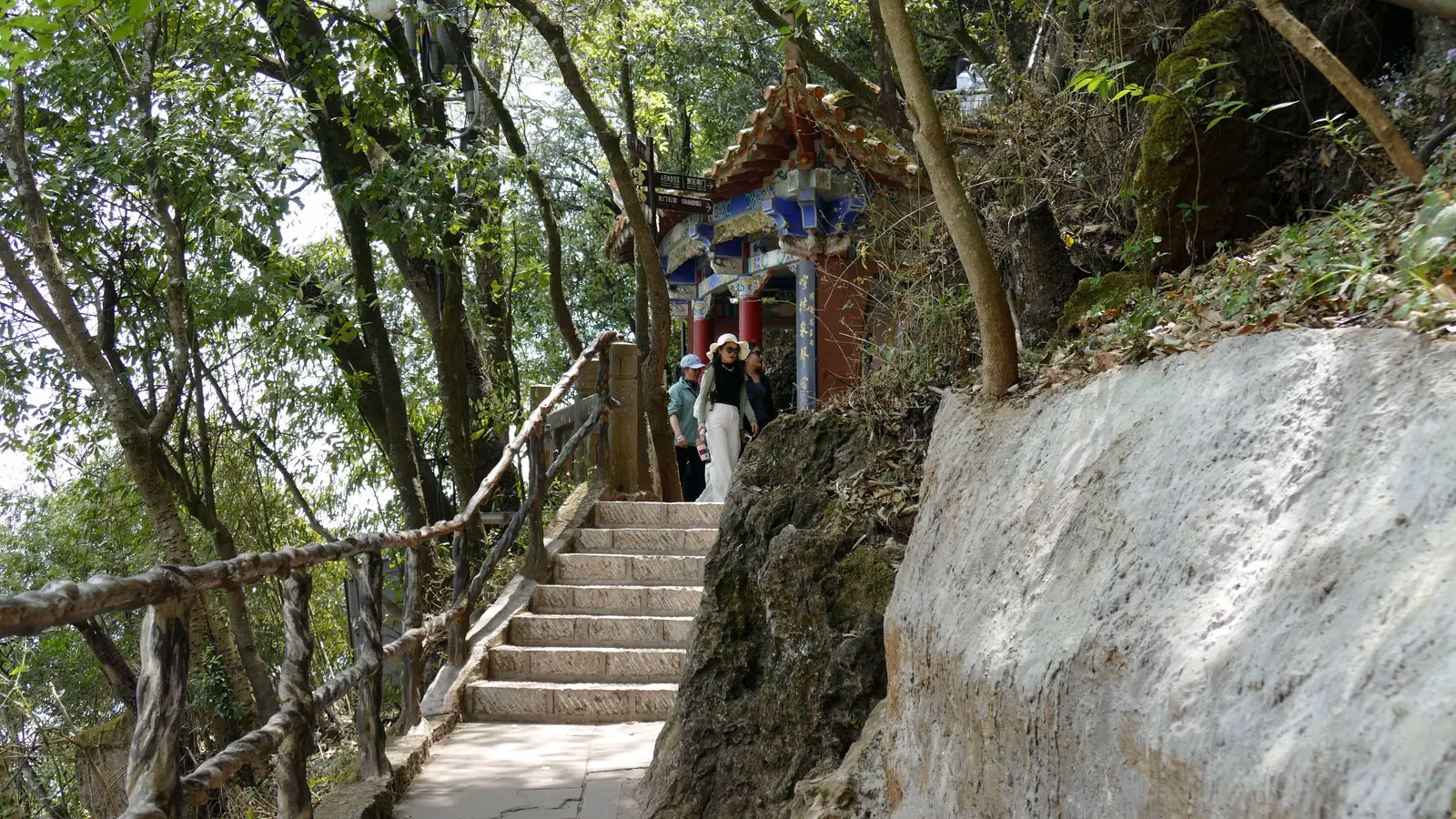 Visitors on stone steps beside a shrine in the Longmen area of Kunming’s Western Hills